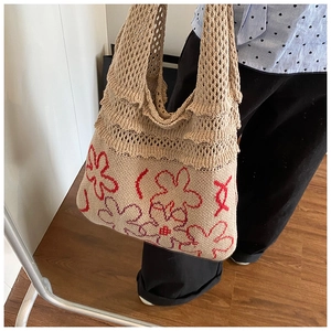 Detailed knit tote bag with red floral patterns and ruffled layers on the shoulder strap