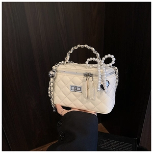 Close-up of white quilted leather bag with pearl bow charm and silver chain strap