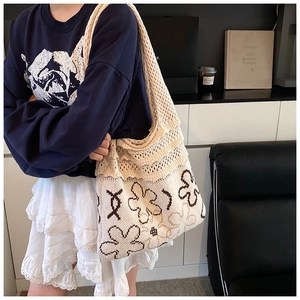 Detail of knitted shoulder bag featuring floral patterns and a mesh weave structure