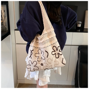 Detail of floral knit tote bag showing intricate crochet texture and beige flower design
