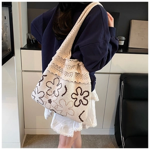 Detail of off-white knitted tote bag with brown flower embroidery and crochet texture