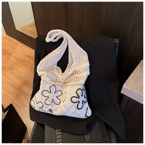 Close-up of cream knit tote bag featuring brown floral patterns and woven texture