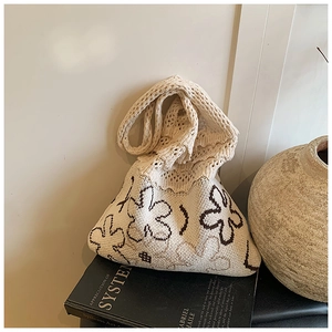 Detail of cream knit crochet tote bag with brown floral patterns on black art books
