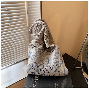 Detail of grey knitted tote bag with blue floral pattern and mesh texture