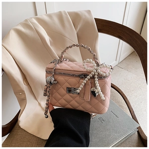 Detail of pink quilted box bag with silver hardware and elegant pearl bow charm