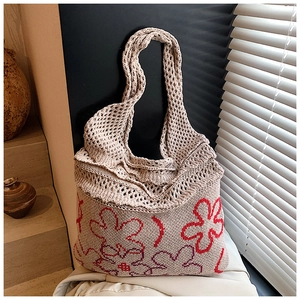 Detailed texture of ivory knitted tote bag featuring red and purple floral patterns