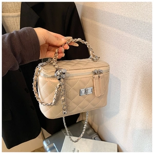 Close-up of beige quilted vanity bag with silver chain handle and metallic twist lock