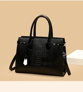 Close-up of black crocodile pattern faux leather handbag with silver stud details