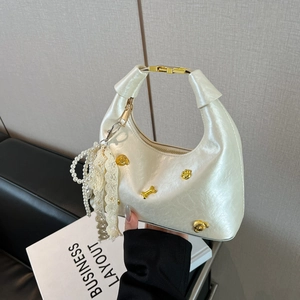 Elegant off-white dumpling bag with pearl luster, gold charms and lace ribbon detail