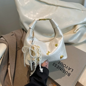 Chic white dumpling bag with pearl charms and gold accents for a stylish look