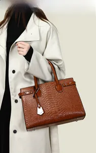 Detail of brown crocodile embossed leather tote bag with silver studs and metal feet