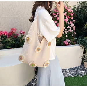 Detail of beige knitted tote bag with 3D floral accents and colorful bead centers