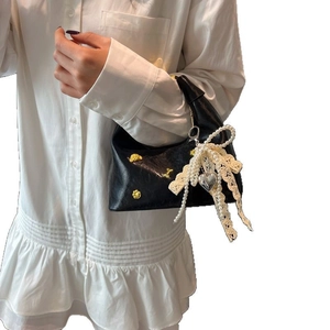 Chic black leather dumpling bag with lace bow, pearls, and gold floral studs