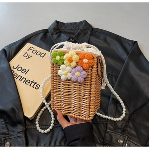 Détail du sac seau en paille avec fleurs en tricot colorées et bandoulière en perles