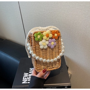 Détail du sac seau en paille tissé main avec fleurs au crochet et poignée en perles