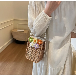Détail du sac seau en paille avec fleurs au crochet et poignée en perles de nacre