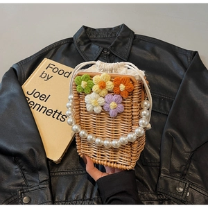 Détail d'un sac en rotin tressé avec fleurs au crochet et anse en grosses perles
