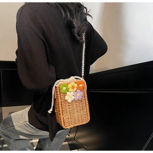Détail du sac en paille tissé avec des motifs floraux au crochet et une bandoulière perle