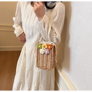 Détail du sac à main en paille tressée avec fleurs au crochet et grande anse en perles
