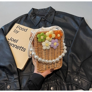 Détail d'un sac en paille tissé à la main avec fleurs en tricot et anse en perles