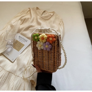 Détail du sac seau en paille avec fleurs au crochet et bandoulière en perles chics