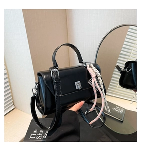 Detailed shot of a black tote bag featuring a silver twist lock and braided rope charm