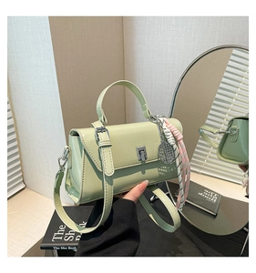 Detail of mint green leather crossbody bag with silver clasp and tennis racket pendant