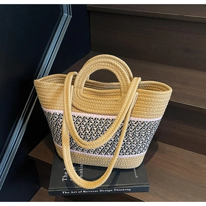 Détail du sac cabas tissé tricolore avec anses rondes posé sur un escalier en bois