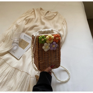 Détail d'un sac seau en paille fait main avec fleurs au crochet et anse en perles blanches