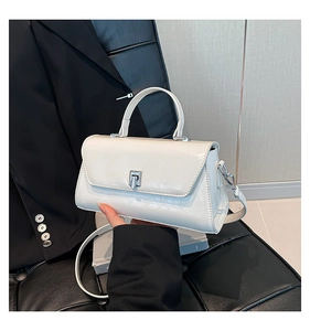 Detail of glossy white pleated leather handbag featuring a silver twist lock and metal hardware
