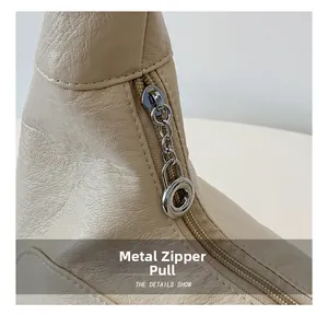 Close-up of high-quality silver metal zipper on textured beige leather shoulder bag