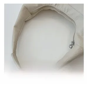 Detail of soft cream leather handle and metallic zipper on a large tote bag