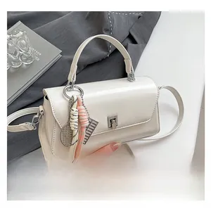 Close-up of cream square handbag with silver lock and unique tennis racket charm