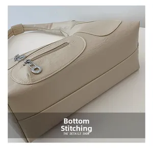 Detail of cream PU leather handbag showing bottom splicing and side zip pocket