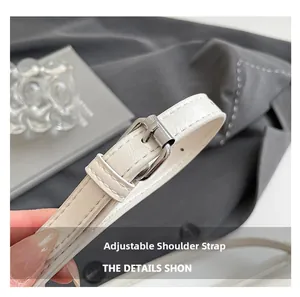 Macro detail of adjustable white leather shoulder strap with silver buckle on handbag