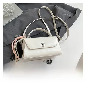Detail of ivory square handbag with metal buckle and decorative woven tassel