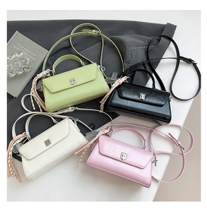 Flat lay of minimalist mini square bags in green, black, cream, and pink with tassel detail