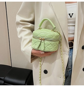 Detail of mini quilted crossbody bag in mint green with double metal zippers and chain strap