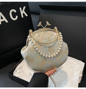 Elegant green brocade shell bag with gold bird clasp and pearl handle in a gift box
