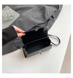 Detail of minimalist black leather crossbody bag with silver twist lock and inner space