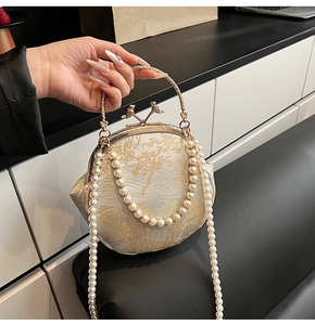 Detail of vintage jacquard evening shell bag with gold embroidery and bird clasp