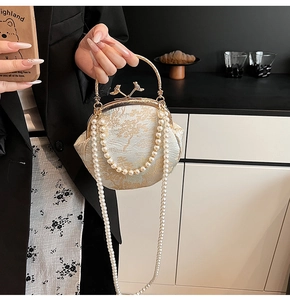 Detail of white brocade evening bag with gold bird clasp and double pearl straps