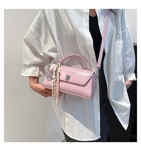 Detail of pink crossbody bag with silver buckle and tennis racket bag charm tassel