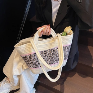 Détail du sac cabas tissé contrasté avec doubles anses et texture bohème sur marches