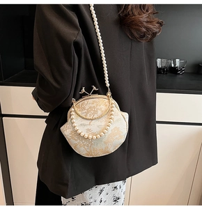 Detail of vintage floral shell bag with bird-shaped clasp and pearl shoulder strap