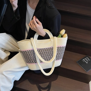 Détail du sac cabas tissé main avec motif géométrique contrasté et deux anses sur l'escalier