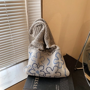 Gray knitted mesh tote bag with blue crochet floral pattern on a bright windowsill