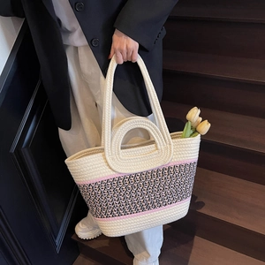 Vue détaillée du sac cabas tissé avec bandoulière géométrique sur escalier en bois