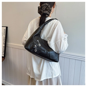 Detail view of black nylon hobo bag with silver metal rings and multi-zippered pockets