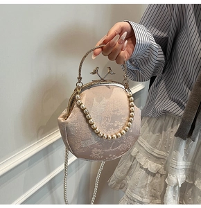 Detail of floral jacquard fabric and golden bird clasp on elegant pearl shell bag